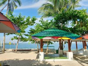 um grupo de guarda-sóis numa praia perto da água em Ohana Resort 