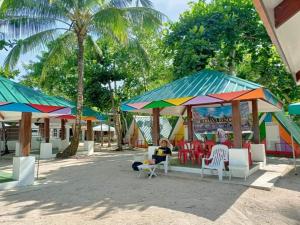 een groep mensen zittend in stoelen onder parasols op een strand bij Ohana Resort 