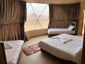 a hotel room with two beds and a large window at Al Rifi Luxury Camp in Wadi Rum