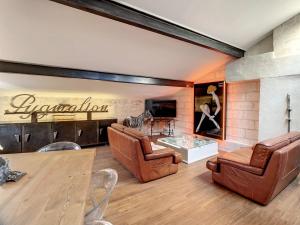 a living room with leather furniture and a wall with a sign at Pygmalion appartement in Avignon