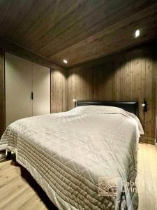 1 dormitorio con 1 cama grande y paredes de madera en Brand new cabin at Moseteråsen Hafjell Ski inout en Øyer
