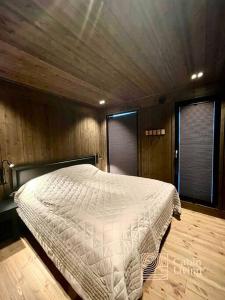 1 dormitorio con 1 cama blanca en una habitación de madera en Brand new cabin at Moseteråsen Hafjell Ski inout en Øyer