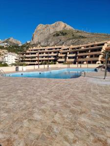 un bâtiment avec une piscine en face d'un bâtiment dans l'établissement Pueblo Mascarat, 50 m al mar, 3 piscios, à Altea la Vieja