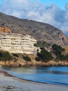 un bâtiment situé sur une colline à côté d'une masse d'eau dans l'établissement Pueblo Mascarat, 50 m al mar, 3 piscios, à Altea la Vieja