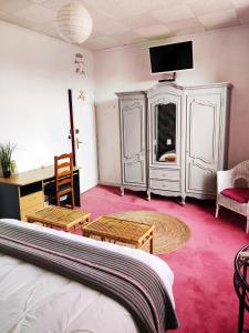 - une chambre avec un lit, un bureau et une télévision dans l'établissement Les Bibasses, à Aillas