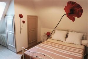 1 dormitorio con 1 cama con una flor roja en la pared en Appart'Aubrac, 
