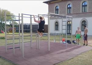a woman jumping in the air on a metal pole at Cala Dei Mori in Livorno