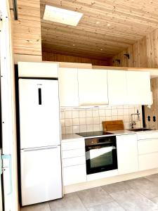 a kitchen with white cabinets and a refrigerator at Neptuni Bed and Kitchen in Varberg