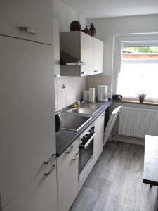 a kitchen with white cabinets and a sink and a window at Ferienwohnung in Hameln am Wald in Hameln