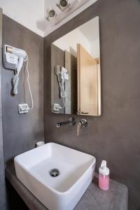La salle de bains est pourvue d'un lavabo blanc et d'un miroir. dans l'établissement Liana Studios, à Mykonos