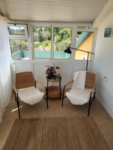 2 sillas y una mesa en una habitación con ventanas en Casa Vida Alegre, en Prazeres