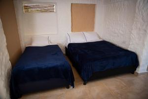 - 2 lits dans une petite chambre avec des draps bleus dans l'établissement Caney 1, à Moniquirá