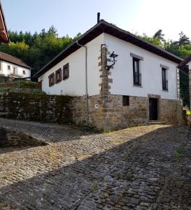 ein weißes Gebäude mit einer Steinstraße davor in der Unterkunft XANDUA Etxea - Selva de Irati - in Izalzu