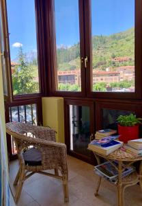 een kamer met een tafel, stoelen en ramen bij Hostal La Serna in Potes