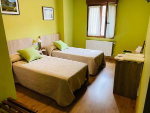 2 camas en una habitación con paredes verdes en Hostal La Serna, en Potes