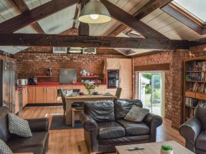 a living room with leather furniture and a brick wall at The Pool House in Hale