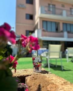 un bicchiere seduto sopra una parete con fiori rosa di Hotel Bel Sogno a Rimini
