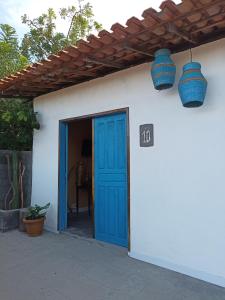a white house with a blue door and two blue lights at Amorada in Santo Amaro