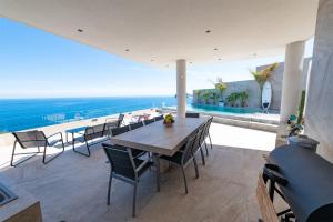 een eetkamer met een tafel en stoelen en de oceaan bij Villa Zambudio in San José