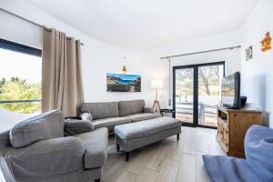 ein Wohnzimmer mit einem Sofa und einem TV in der Unterkunft CoolHouses Algarve, Luz, 3 Bed villa, 1 bed studio, heated pool & jacuzzi, sea views, Casa Pequena in Luz