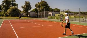 a group of people playing tennis on a tennis court at Mobil Home excellence 6 personnes au camping Siblu Mer et Soleil, Saint George d'Oléron in Les Sables Vignier