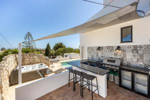 eine Küche mit einer Theke und eine Kücheninsel mit Hockern in der Unterkunft CoolHouses Algarve, Luz, 3 Bed villa, 1 bed studio, heated pool & jacuzzi, sea views, Casa Pequena in Luz