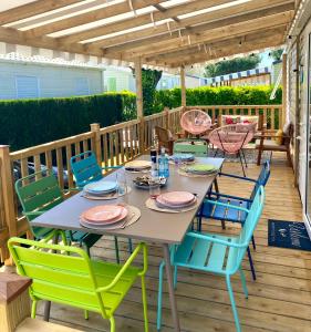 a table and chairs on a deck with a pergola at Mobil Home excellence 6 personnes au camping Mer et Soleil, Saint George d'Oléron in Les Sables Vignier