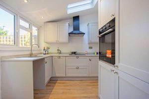 a kitchen with white cabinets and a sink and an oven at Relax with the whole family at the cosy cottage - Business rates in Marlborough