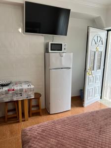 uma cozinha com um frigorífico, uma mesa e uma porta em Moradia da Ilda - Casas de Férias Nazaré na Nazaré