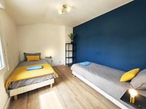 a bedroom with two beds and a blue wall at Royal Terrace - Maison plage & Parking privé in Dunkerque +17 photos