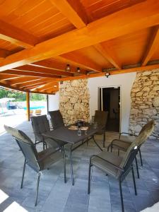 a patio with a table and chairs and a stone wall at VILA IRENA in Gostinjac