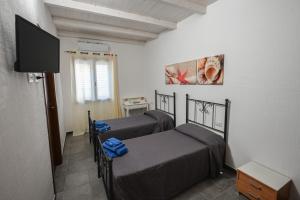2 camas individuais num quarto com uma televisão em B&B Su Neulagi em Triei