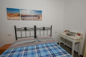 a bedroom with a bed and a desk with two pictures on the wall at B&B Su Neulagi in Triei