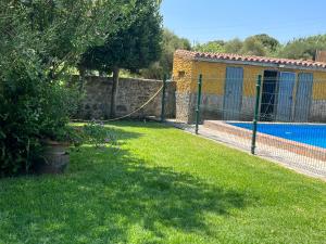 a fence next to a yard with a swimming pool at Chalet Valdevaqueros - Gran piscina y 5 min playa in Tarifa