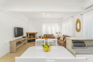 Maela Luxury Suite في ماليا: غرفة معيشة بيضاء مع طاولة وأريكة