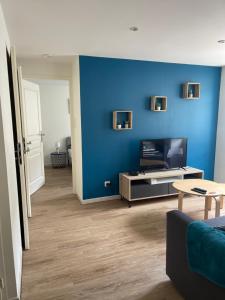 a living room with a blue wall and a tv at Superbe Appartement in La Côte-Saint-André