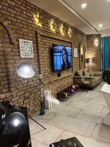 a living room with a brick wall with a flat screen tv at Khan Saray in As Sulaymānīyah