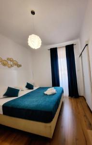 a bedroom with two beds with blue sheets and a chandelier at Apartments Miljas 2 in Dubrovnik