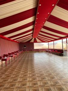 Al Rifi Luxury Camp في وادي رم: غرفة كبيرة بسقوف وكراسي حمراء وبيضاء