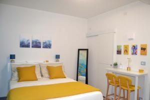 a bedroom with a bed with yellow pillows and a desk at Room&Chiaia in Naples