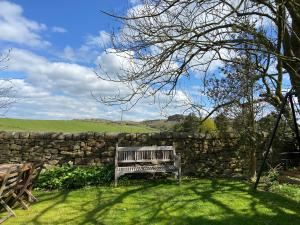 a wooden bench sitting in front of a stone wall at North Farm in Hexham