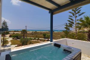 bañera de hidromasaje en el balcón con vistas al océano en Coralli Beach Apartments, en Mikri Vigla