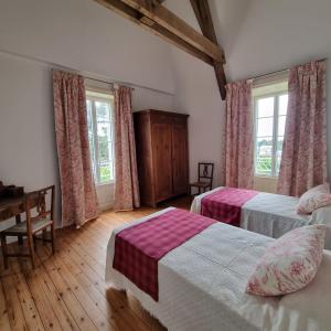 1 dormitorio con 2 camas, mesa y ventanas en Chambres d'hôtes Château de Saint Etienne du Bois, en Saint-Étienne-du-Bois