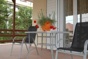 pomarańczowa waza na stole z dwoma krzesłami w obiekcie Bright and airy home 50 meters from the beach w mieście Xylokastron