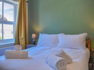 ein weißes Bett mit Handtüchern und einem Fenster in der Unterkunft Ellies Nook in Ireby