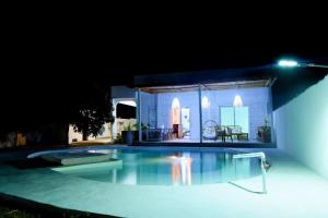 a swimming pool in front of a house at night at Mykolodge Majunga in Amborovy