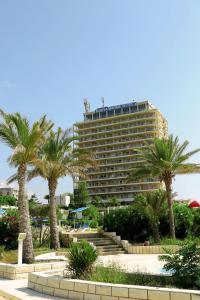 a large building with palm trees in front of it at Rabiya Marine Hotel in Ţabarjā