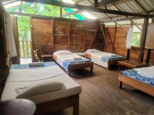 a room with three beds in a wooden house at Ecohotel Bahía Terco in Nuquí