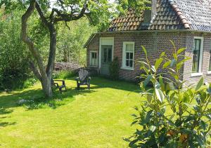 a house with a chair and a bench in a yard at Fakânsjehûs Sfeervol met fijne tuin in Irnsum