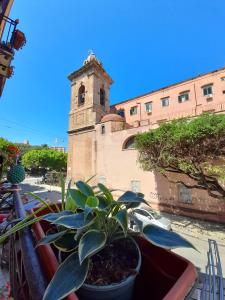 a potted plant sitting on a balcony with a clock tower at Sant'Oliva28 in Palermo